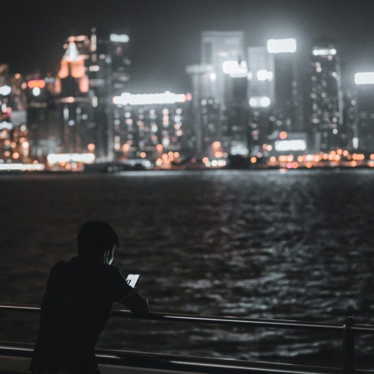 man in black hoodie standing on bridge during night time