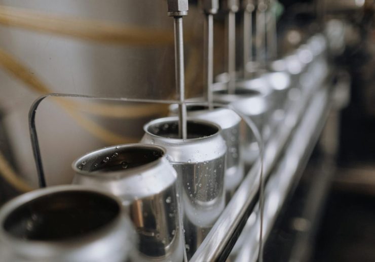 Detailed view of an industrial canning process with aluminum cans on an automatic assembly line.