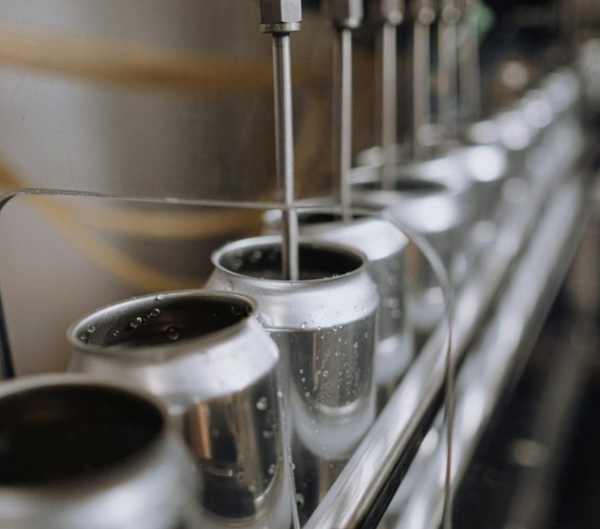 Detailed view of an industrial canning process with aluminum cans on an automatic assembly line.